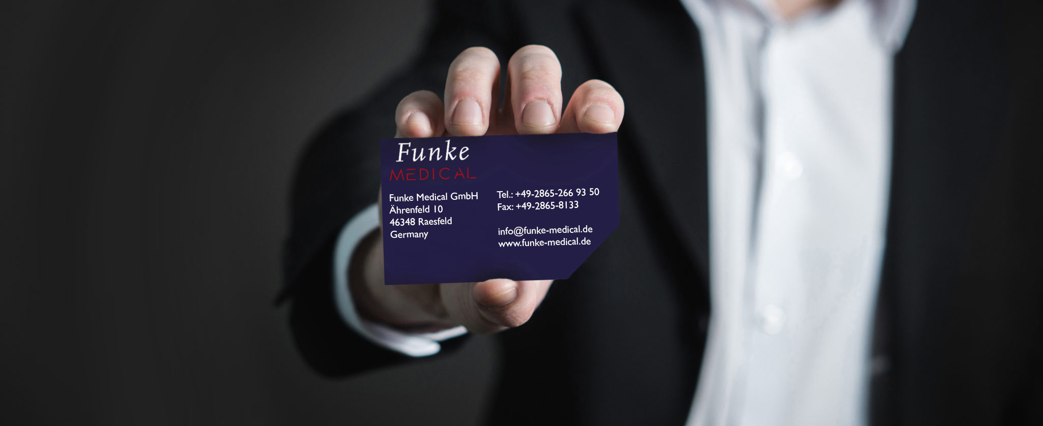 Man in suit holds a Funke Medical business card into the camera