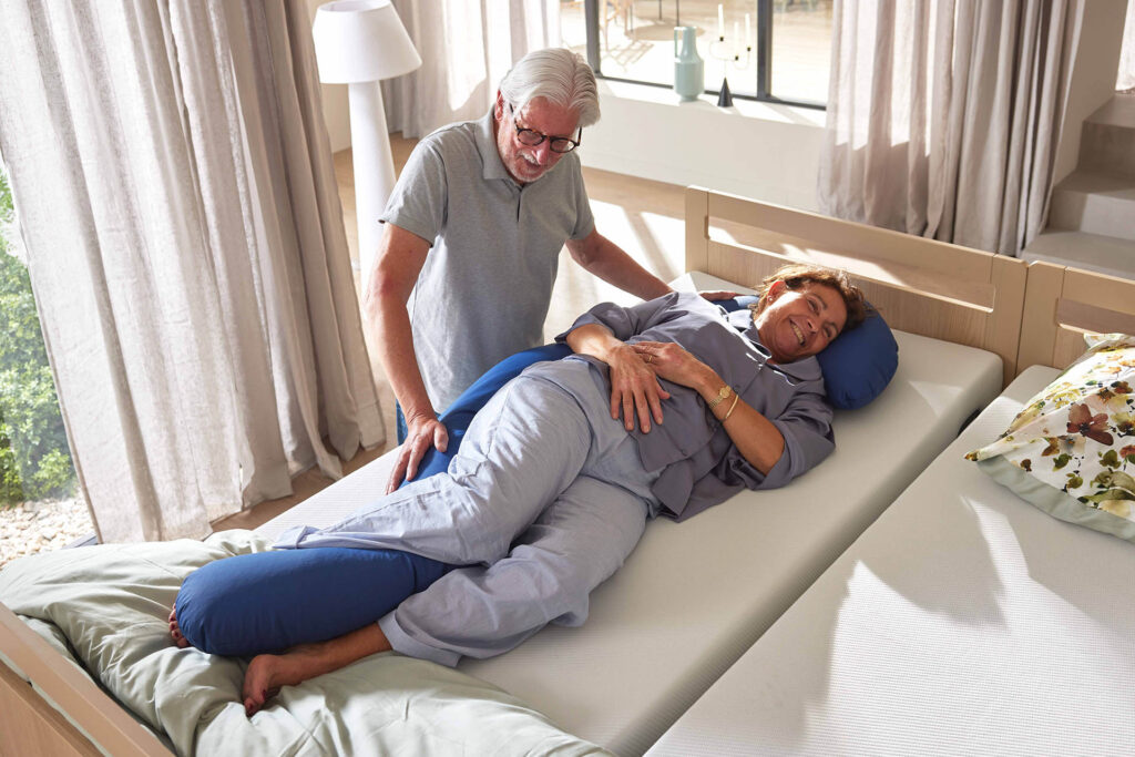 Pfleger positioniert seine Patientin mit dem Hilfsmittel Full Body Positionierungskissen in der Seitenlage