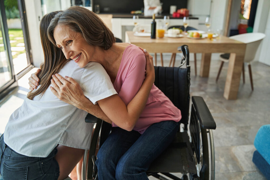 Frau im Rollstuhl umarmt ihre Tochter