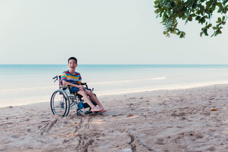 Laughing boy in a wheelchair on the beach